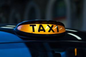 An illuminated taxi sign on the top of a car